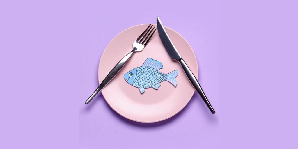 A paper fish sits on a plate in the middle of a purple background