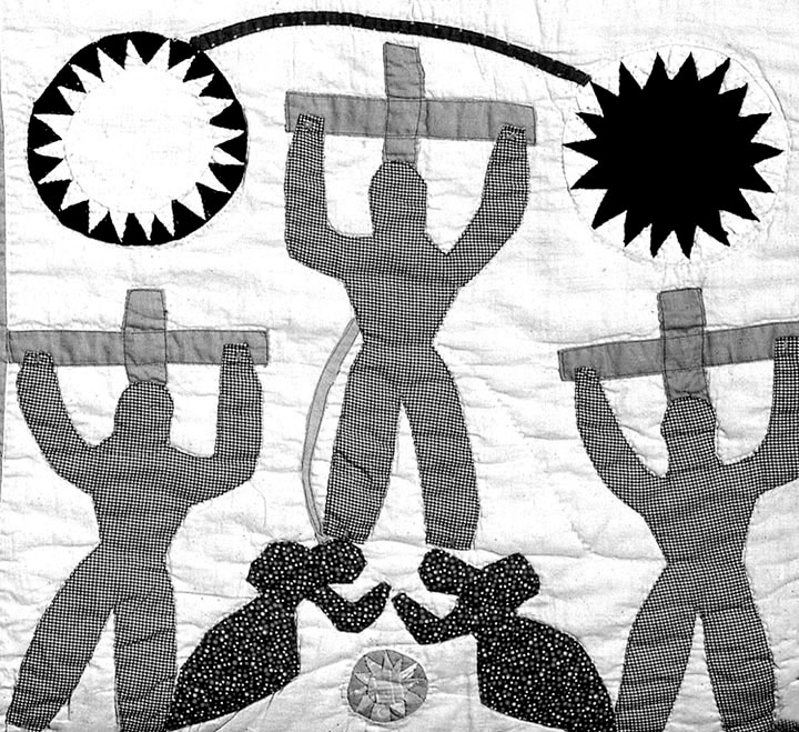 A black and white quilt panel of three figures on three crosses, with two figures at the feet of the cross in the middle
